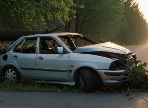 Разбитая машина запуталась в дереве на обочине проселочной дороги на рассвете