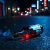Сцена ночной городской жизни с мигающими синими и красными огнями, размытое движение, предполагающее динамичное событие, разбитая бутылка на земле, без людей и лиц, кинематографическое освещение, 8k, гиперреалистично.